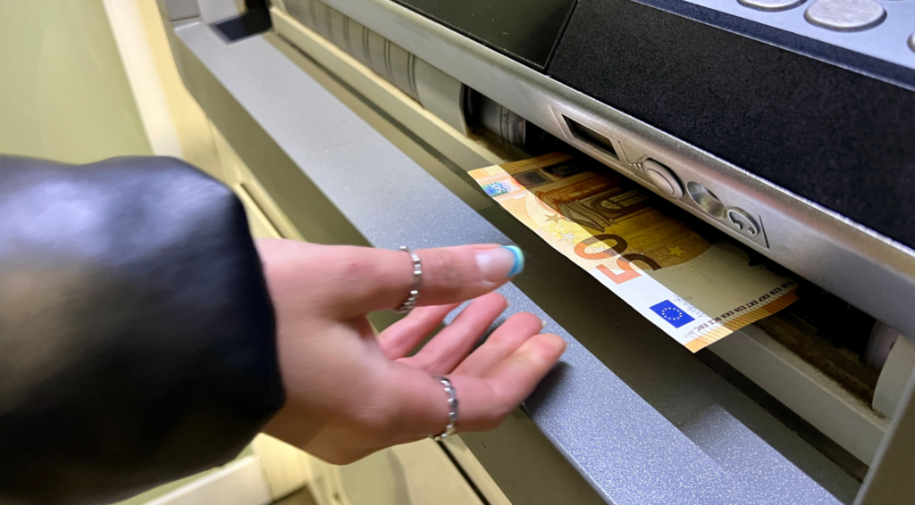 ATMから現金を受け取る場面で、ブランド 買取の入金や現金化を表現